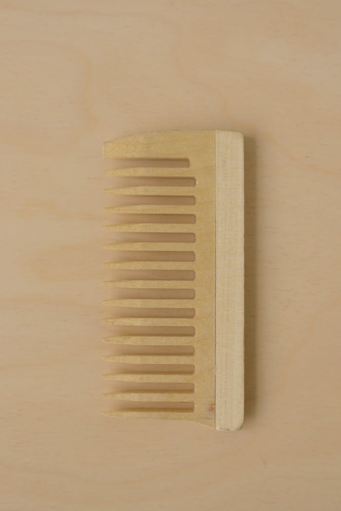 gallery-02 A wooden comb laid flat on a beige background, captured in a minimalist style.